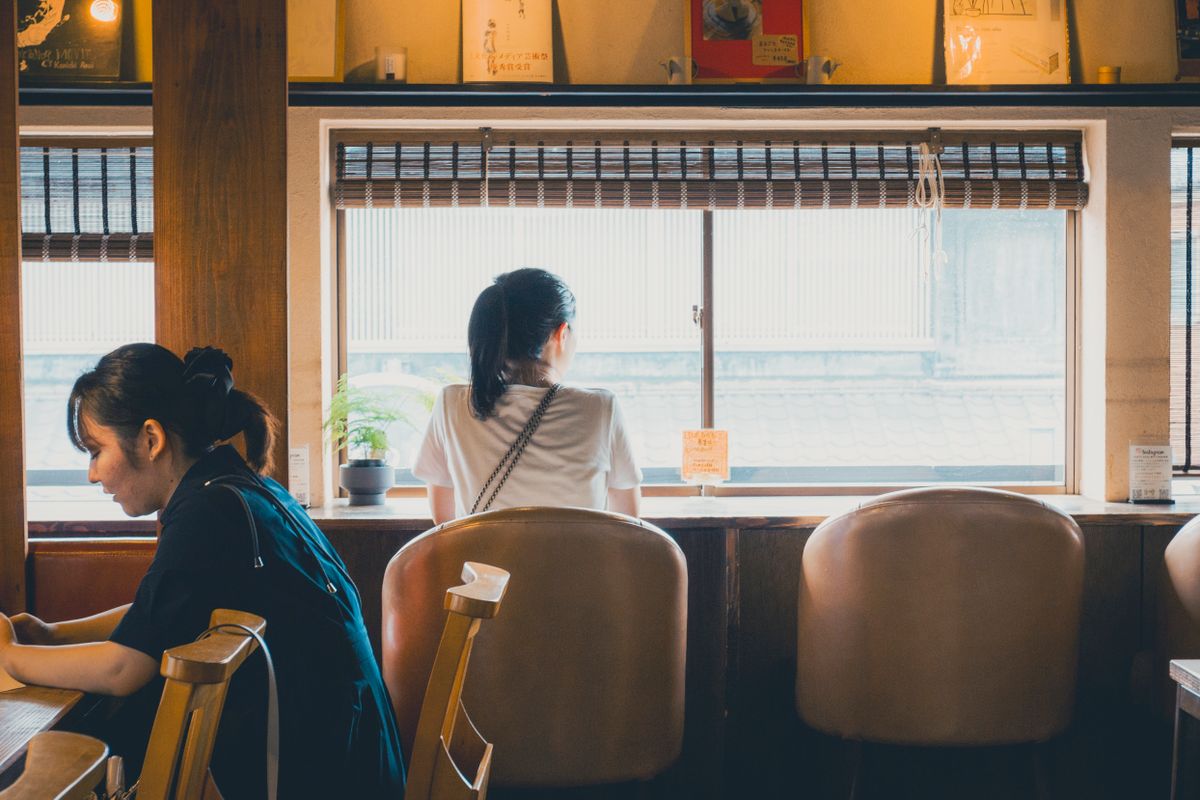 窓際の席でくつろぐお客様がいる、小さなお店の店内