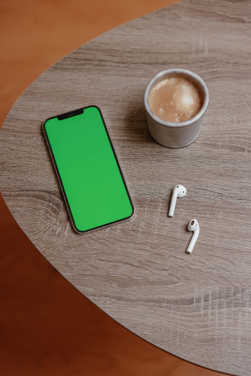 木のテーブルに置かれたスマートフォンとコーヒー